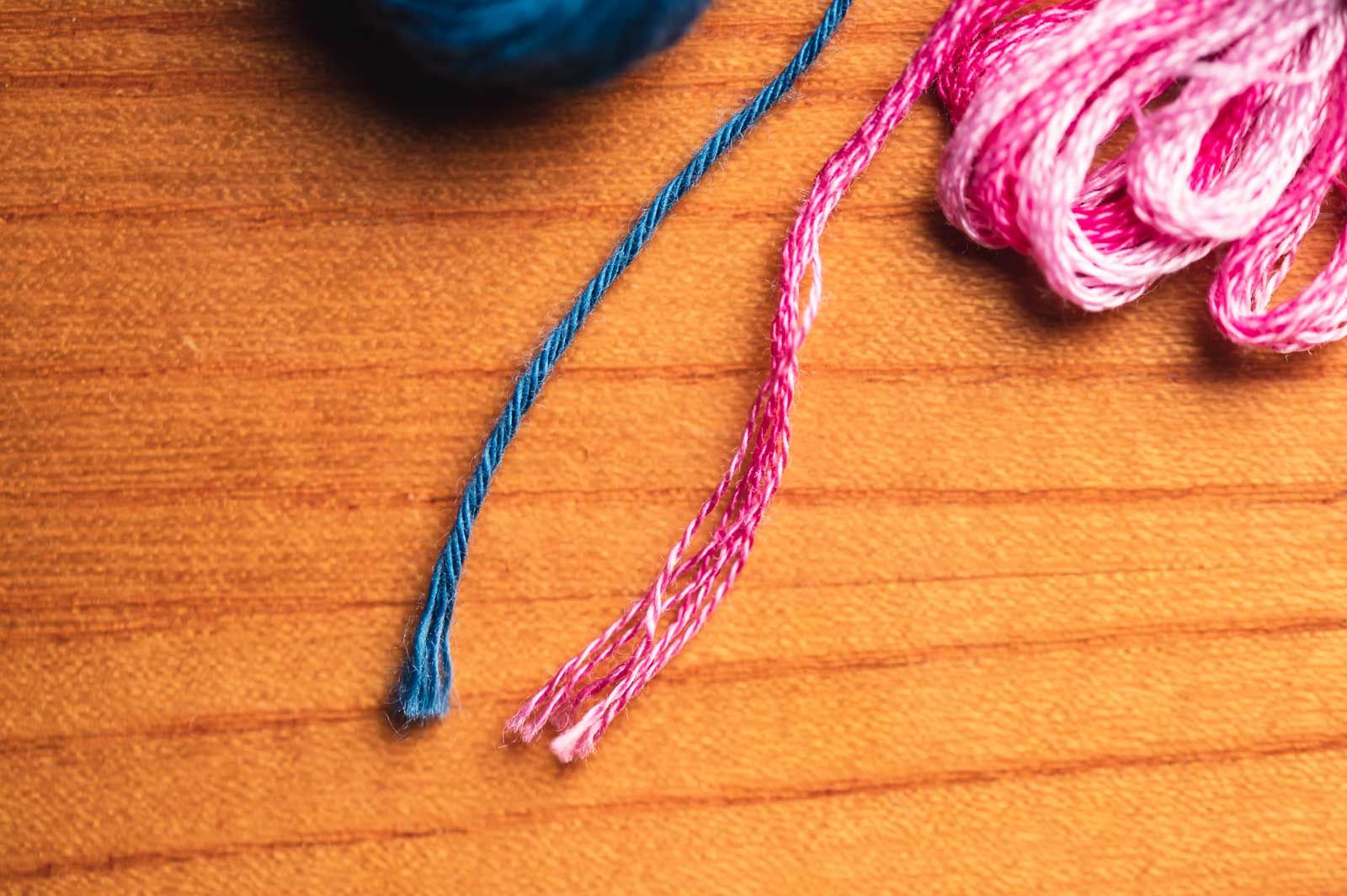 Blue matte sashiko thread and pink shiny embroidery floss on a table