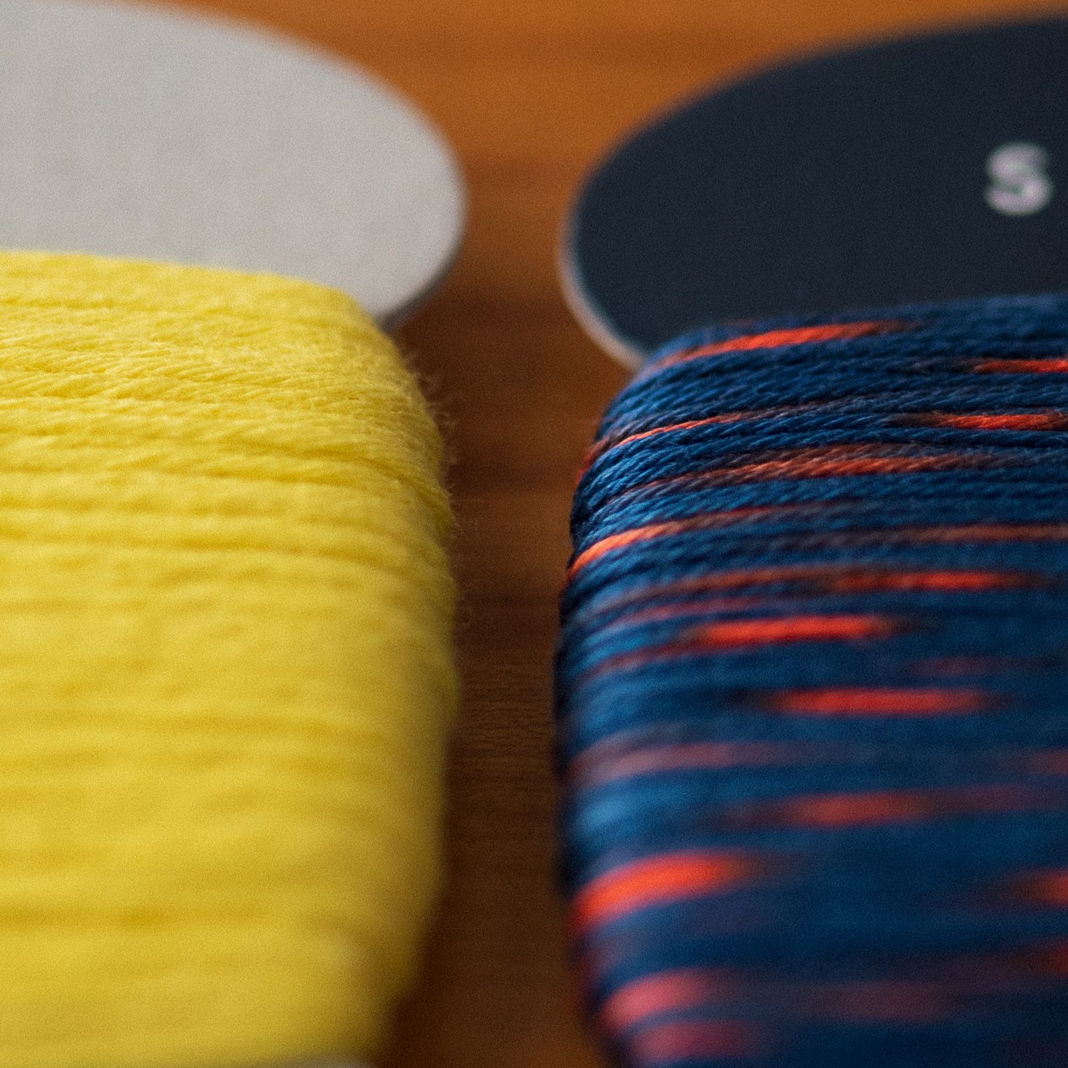 Close-up of yellow kogin thread vs red and blue sashiko thread. Kogin thread visibly fuzzier.