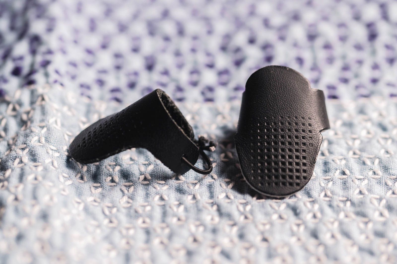 Two leather sashiko thimbles on a sashiko cloth