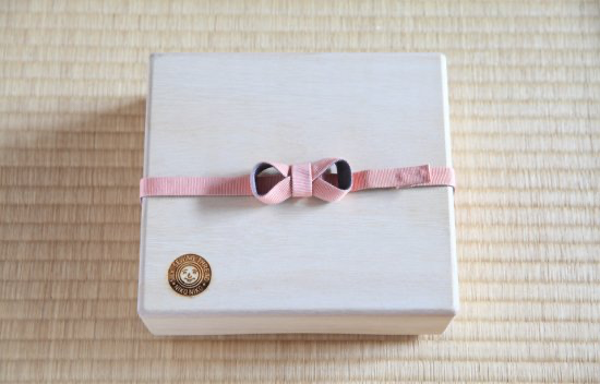 Wooden storage box for sewing utensils with a pink ribbon on top