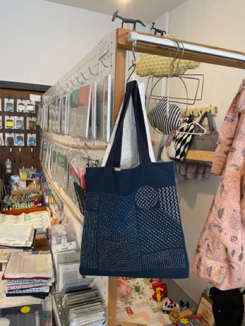 A tote bag with sashiko stitching hanging in a store.
