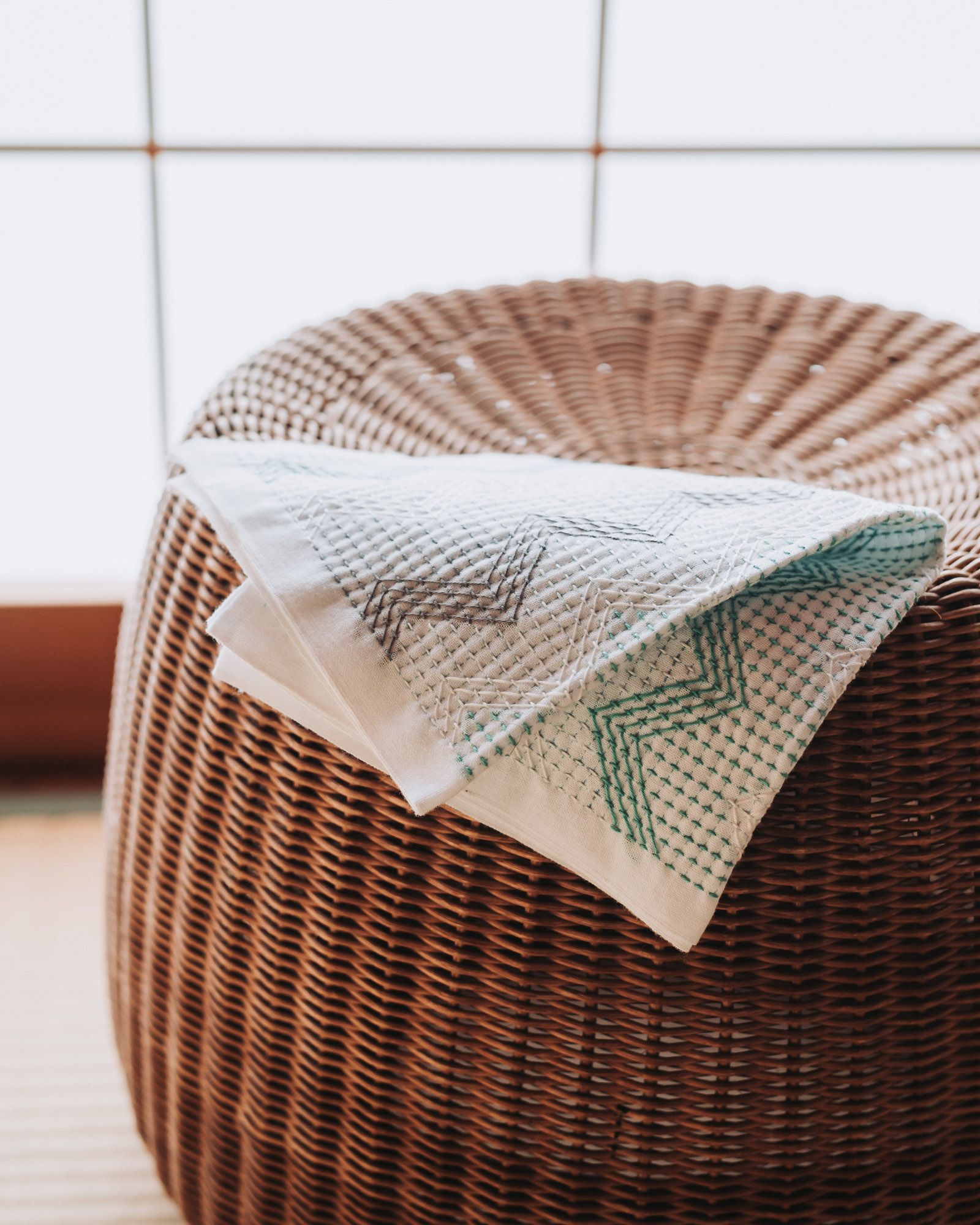 Sashiko cloth lying on top of a rattan chair in the sun.