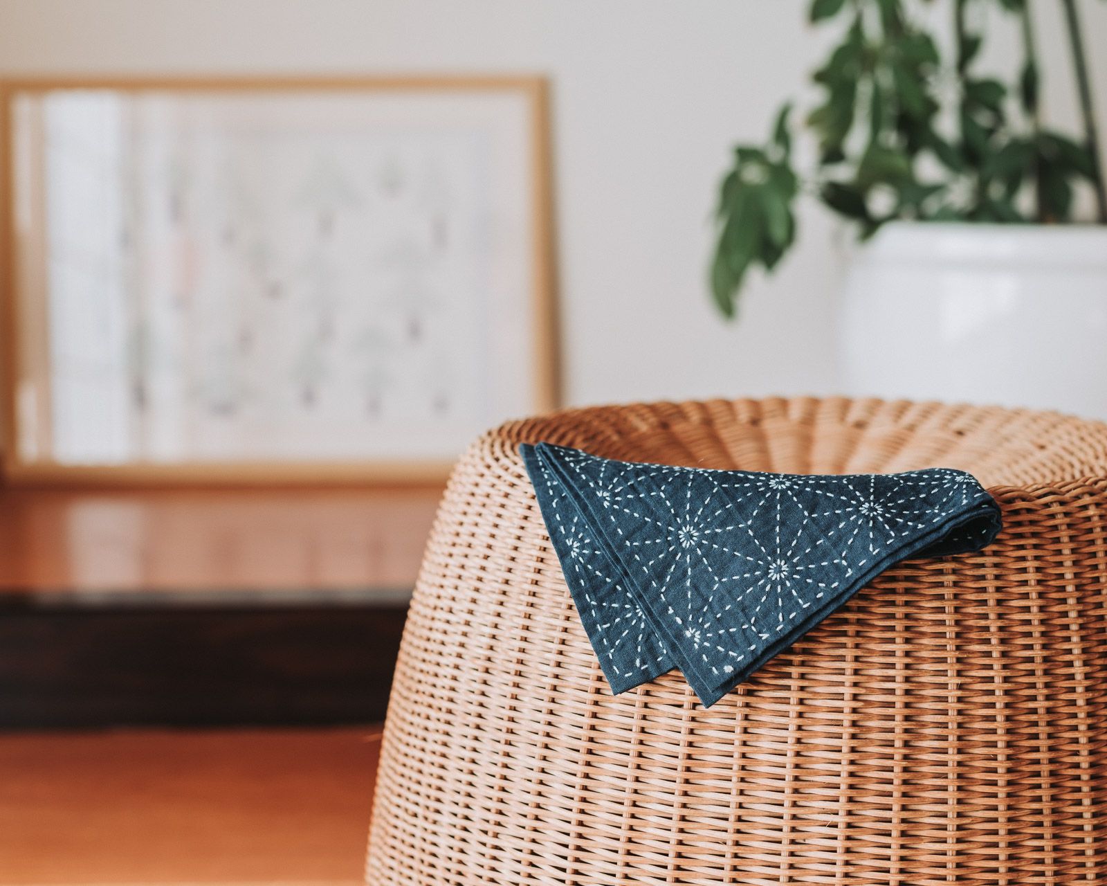Indigo sashiko cloth with hemp leaf pattern lying on a rattan chair.