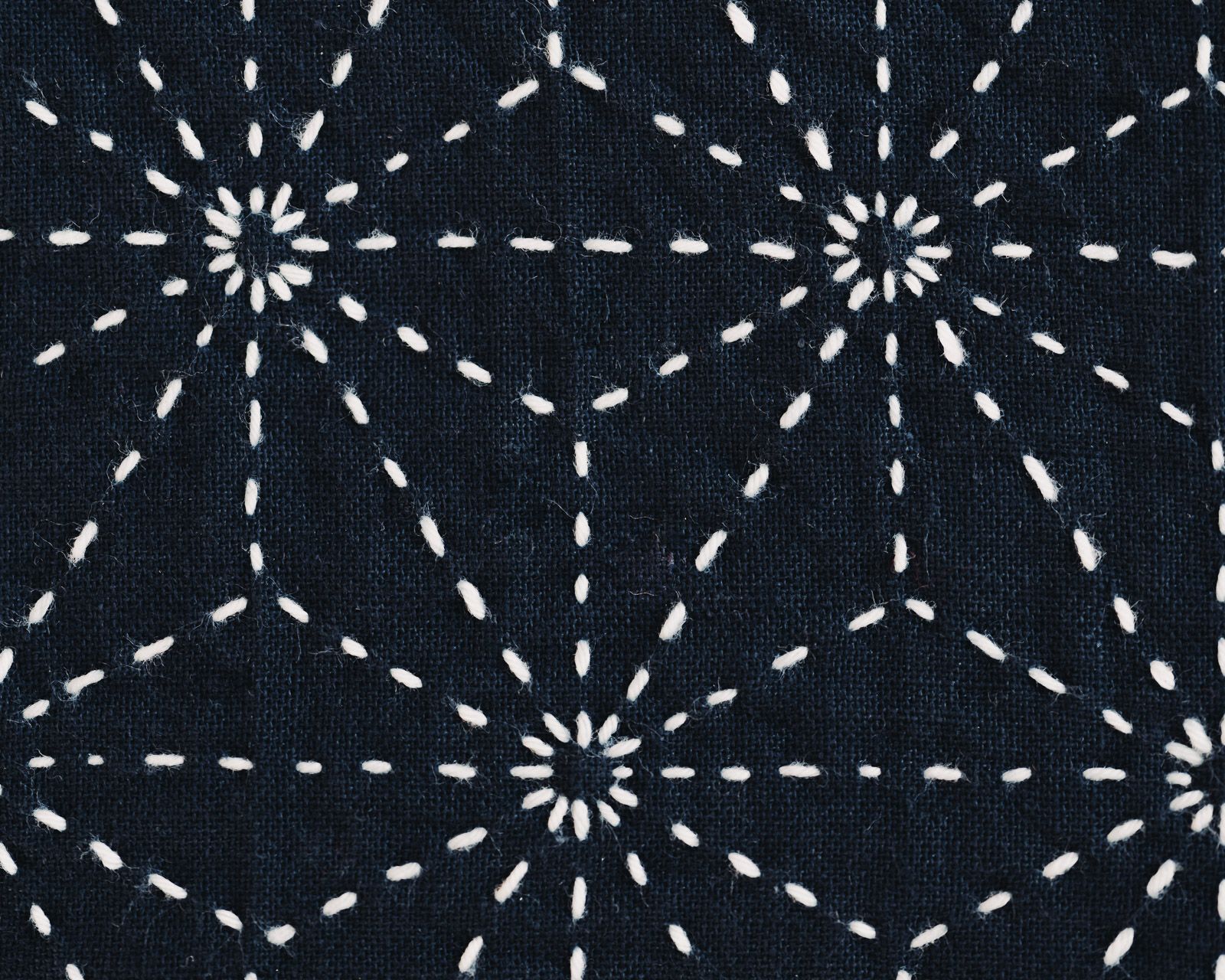 White asanoha sashiko stitches on indigo cloth.