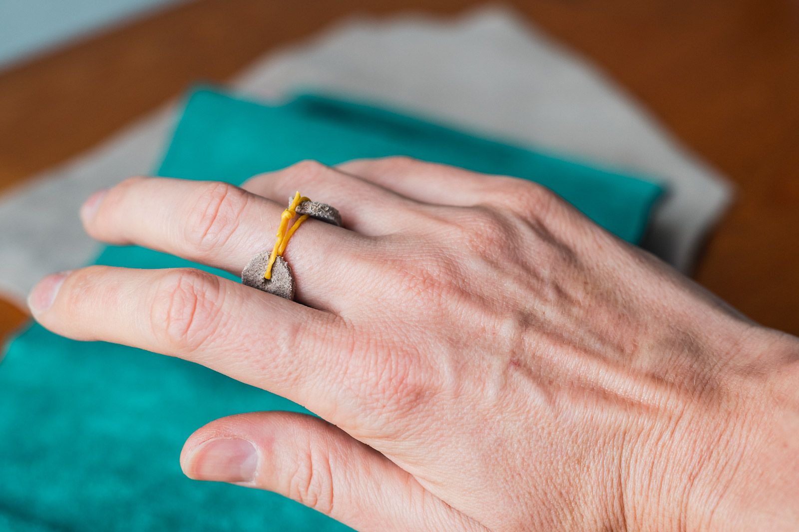 Palm thimble on a finger with a bit of tied string visible.