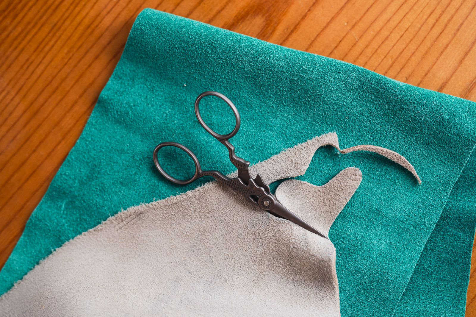 Scissors half way through cutting out the form of a palm thimble from leather.