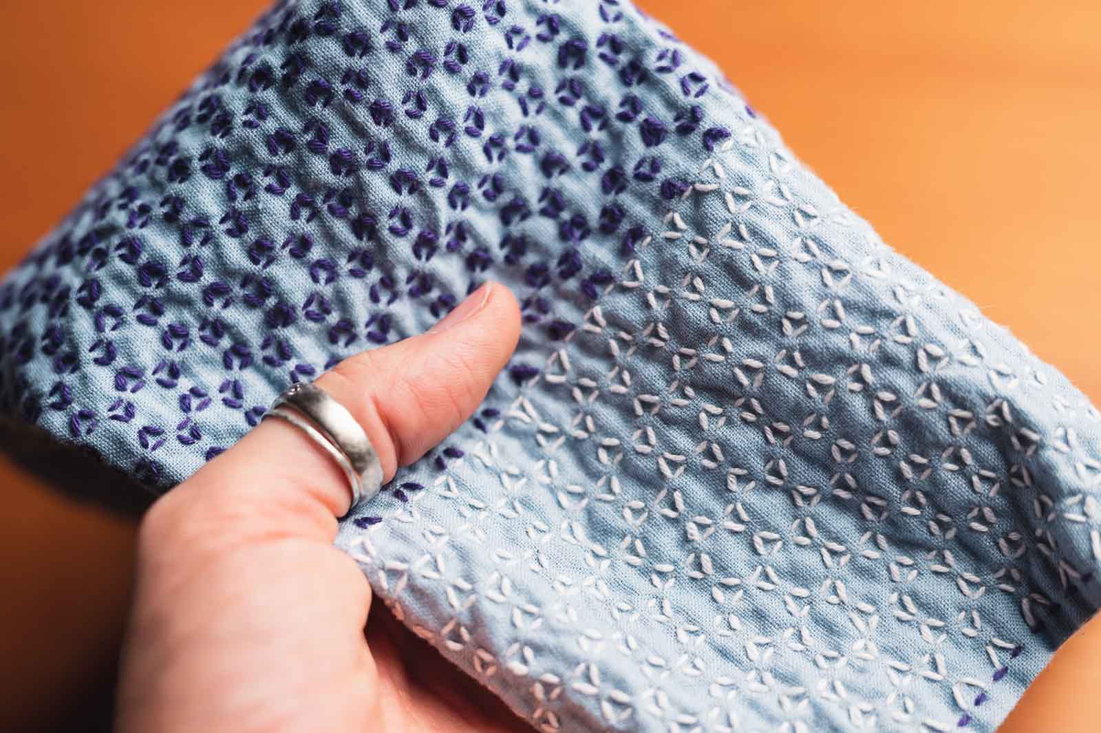 A kitchen cloth in blue with violet and white thread forming the kagome sashiko pattern.