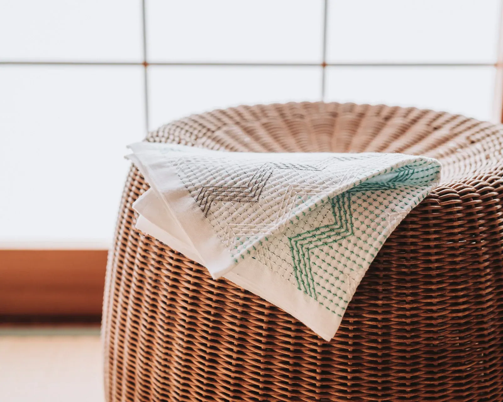 A sashiko dishcloth draped across a rattan stool.