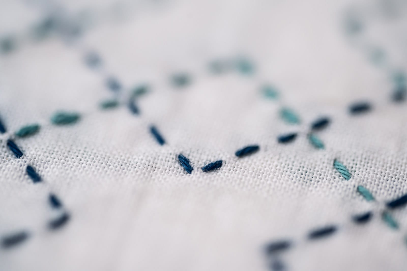 The sashiko pattern kasanemasusashi in two different shades of blue on white fabric close up