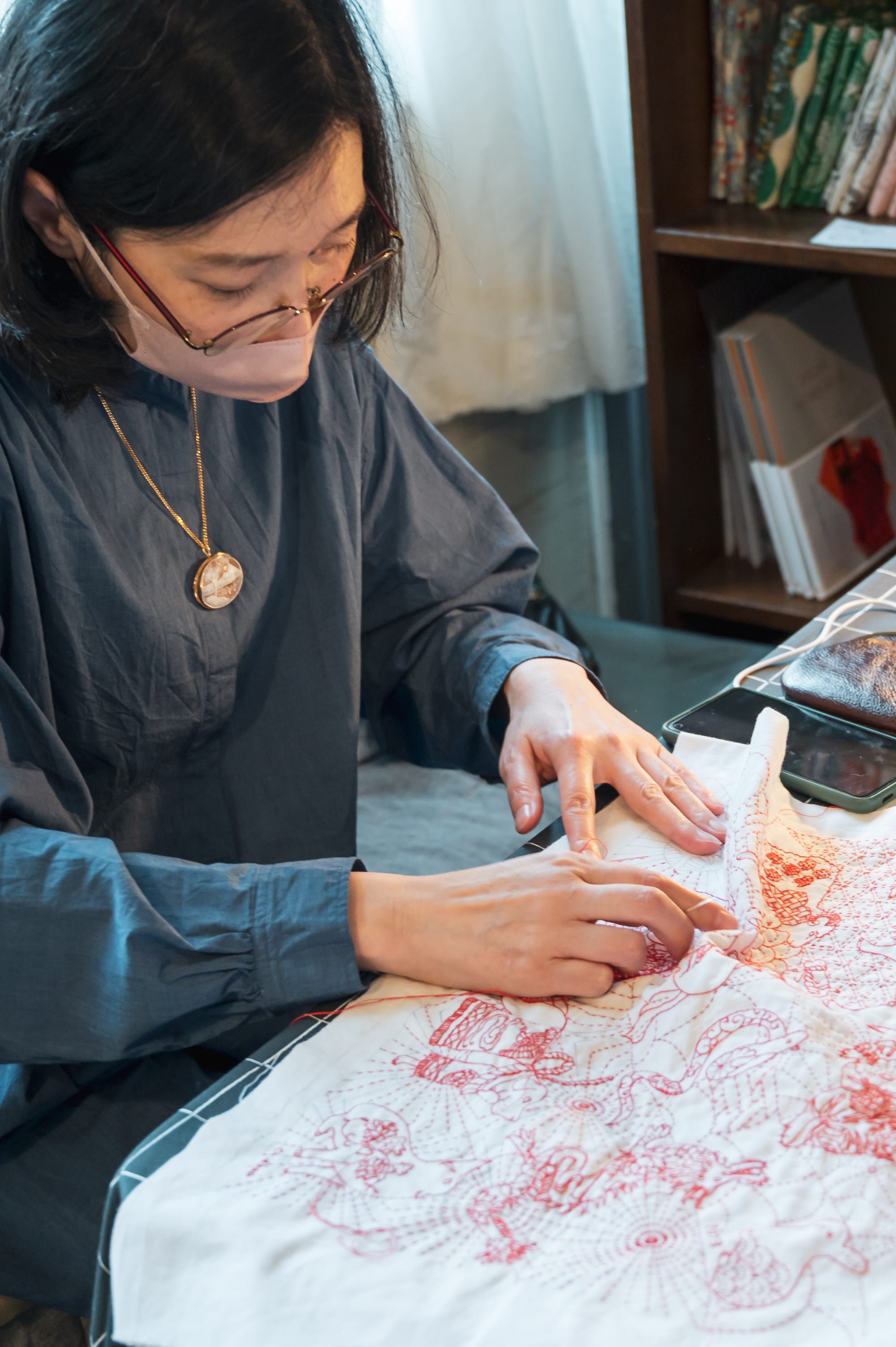 Sashiko artist Chiebaa-chan explaining her technique while working on a self-designed zodiac design in red thread on white.