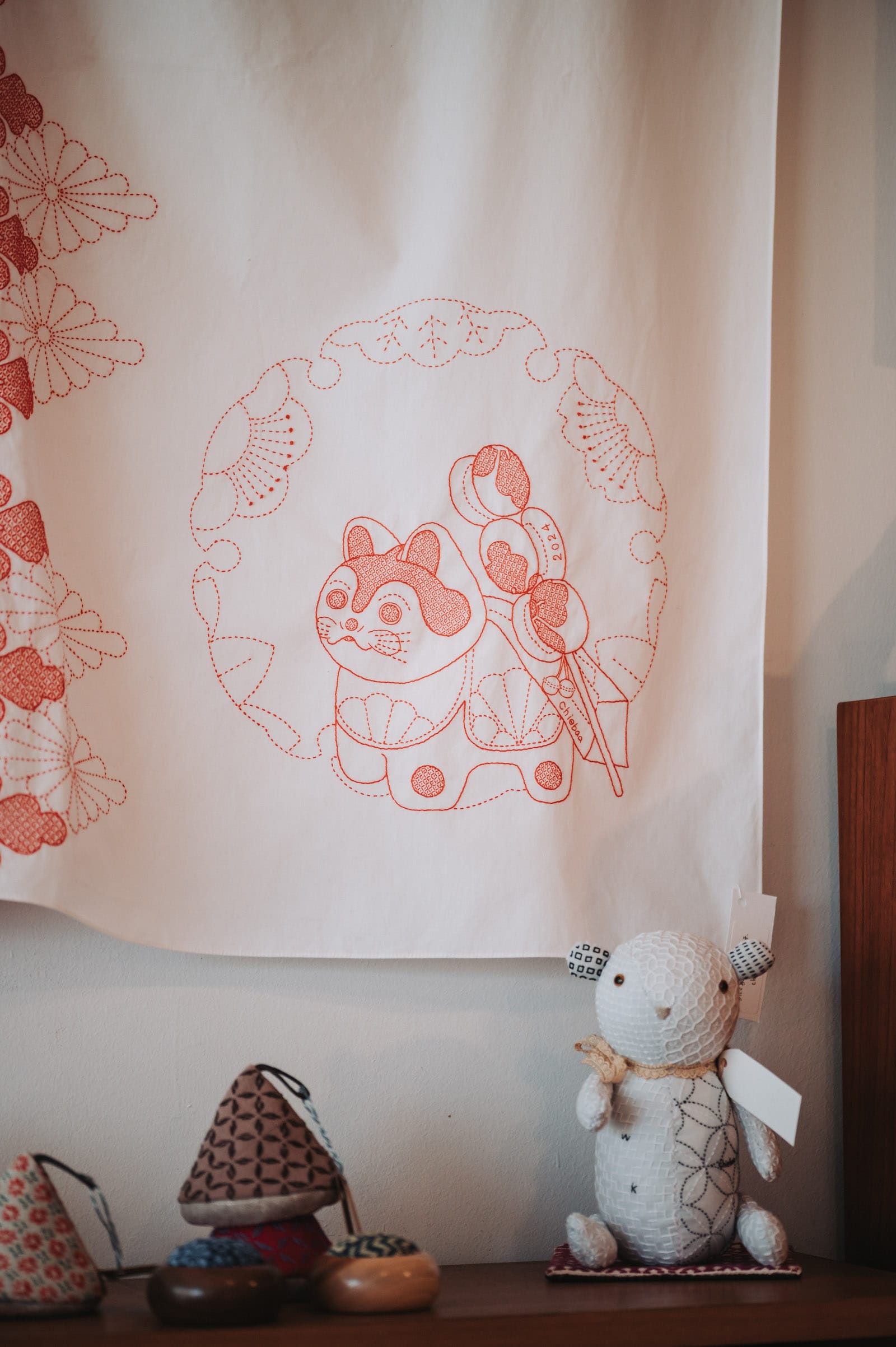 Handmade goods: a teddy bear with sashiko patterns all over, and a cloth with a Japanese dog in red thread by Chiebaa-chan, pot holders and needle cushions.