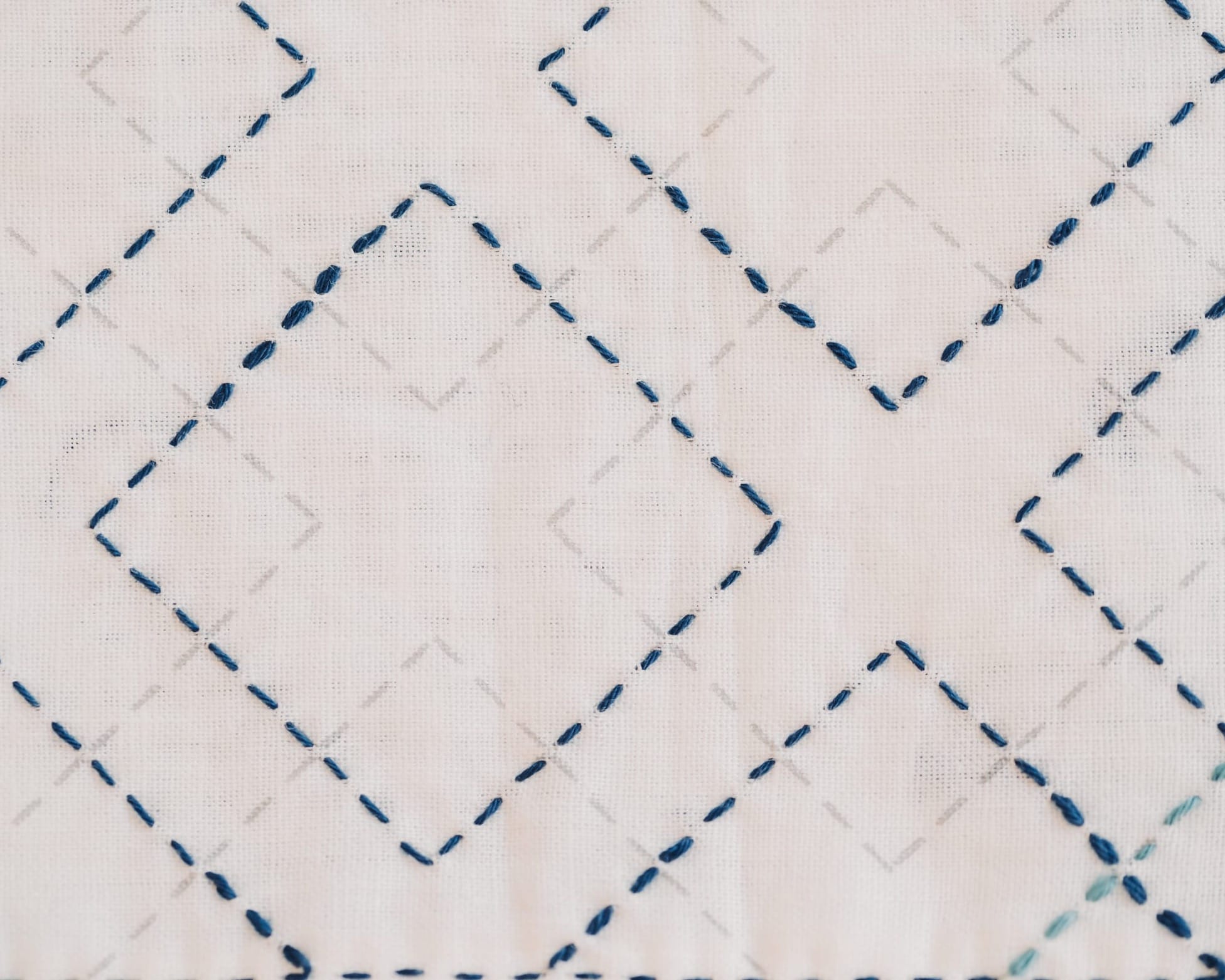 Pre-printed fabric with the kasanemasusashi sashiko pattern partly filled in blue thread on white fabric
