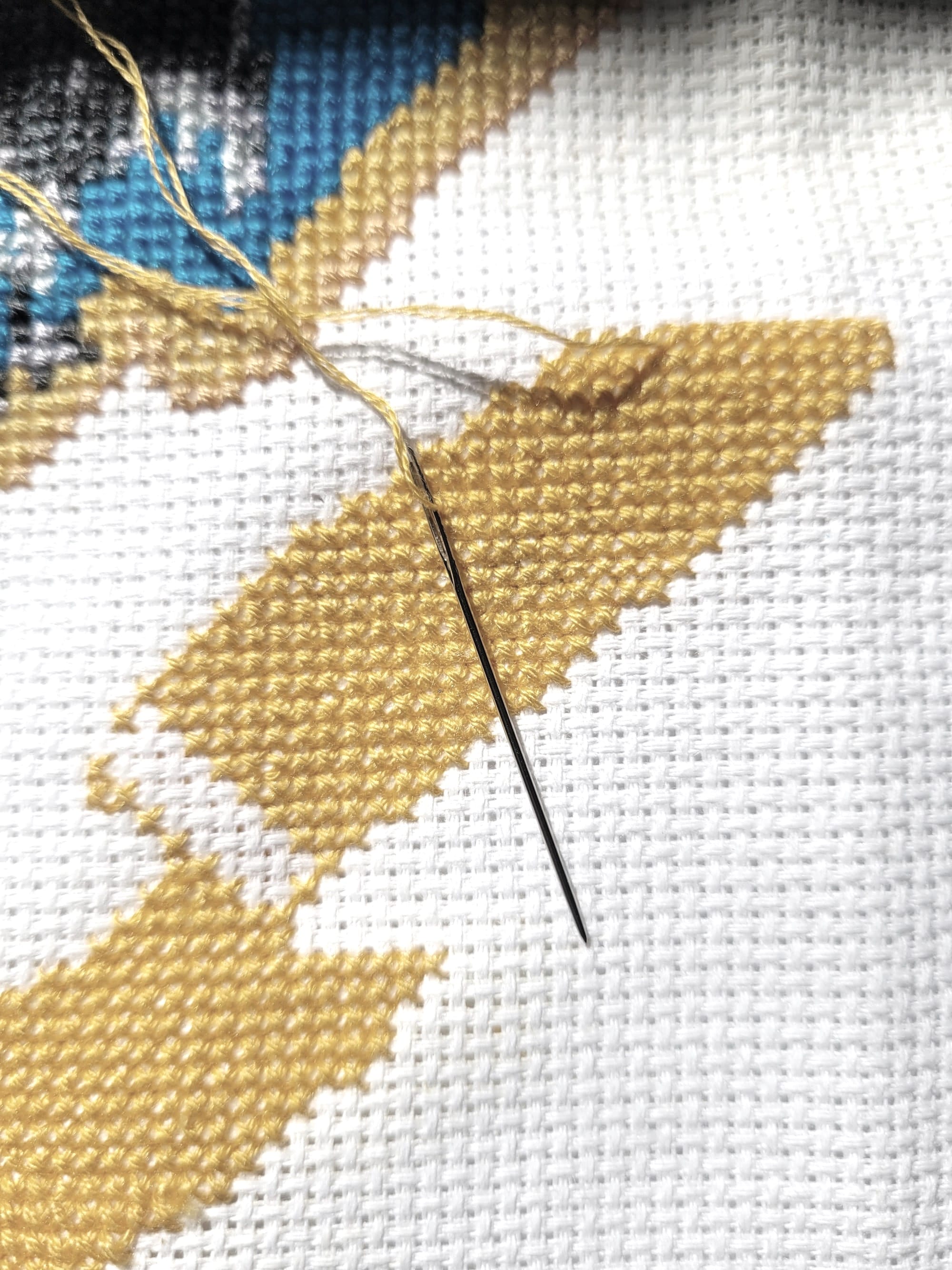 Representative image of cross stitching in yellow thread on white fabric
