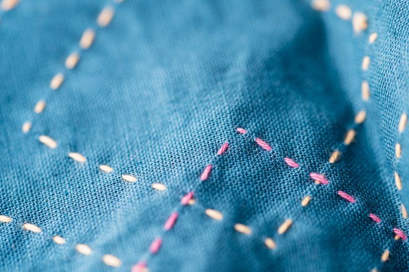 Straight pink and yellow sashiko stitches on teal fabric